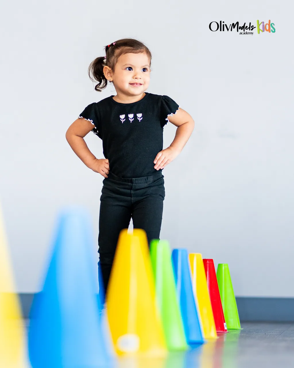 Pequeña talento de Oliv Models Kids posando con conos psicomotrices al frente