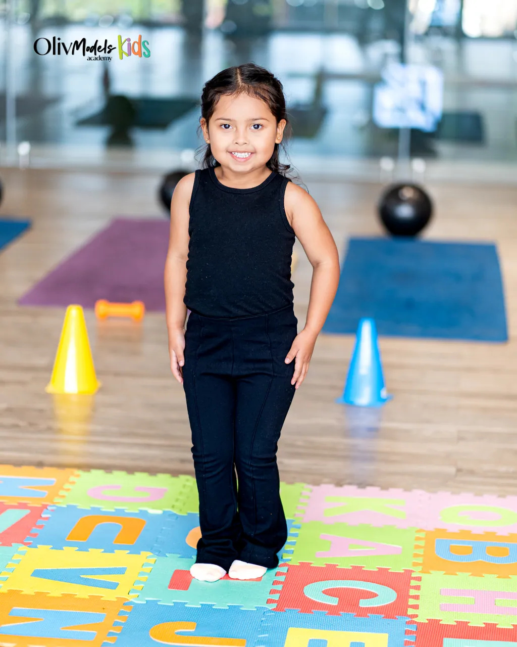 Niña de Oliv Models Kids sobre tapete alfabeto, postura de modelo